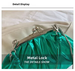 Détail du sac plissé vert métallisé avec un fermoir sphérique argenté et une chaîne