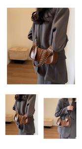 Close-up of vintage brown leather bag with metallic rivet patterns and wide shoulder strap