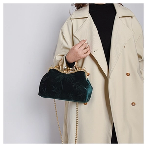 Detail of dark green velvet handbag featuring bamboo leaf texture and pearl gold clasp