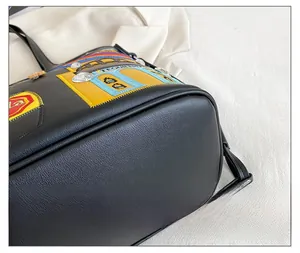 Close-up of rounded corners and colorful patches on the black leather tote bag