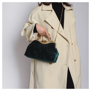 Detail of dark green velvet shell bag with vintage pearl clasp and gold chain strap