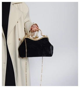 Detail of black velvet evening clutch with leaf relief pattern and pearl snap closure