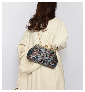 Detail of vintage floral embroidery on black satin crossbody bag with gold metal clasp