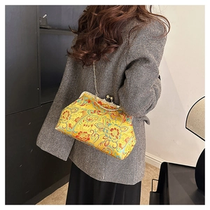 Detailed view of yellow floral embroidery silk bag with vintage metal clasp and chain