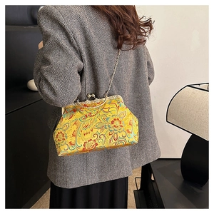 Detail of yellow satin vintage kiss-lock bag with floral embroidery and gold metal chain