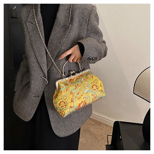 Close-up of vintage yellow silk embroidery handbag with floral patterns and gold metal clasp