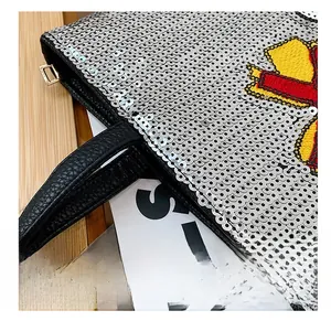 Detail of silver sequins, black litchi grain leather handle and golden hardware on tote