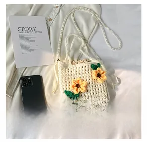 Detail of hand-woven cream bucket bag with yellow sunflower accents and pearl strap