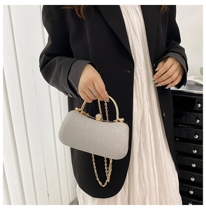 Detailed view of silver glitter evening clutch with gold metal handle and rhinestone clasp