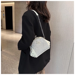 Detail view of white rhinestone shell bag with metal rivets and chain strap on model