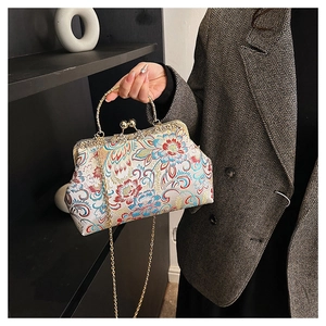 Close-up of white silk bag with floral embroidery and golden metal frame handle