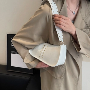 White crescent underarm bag with gold studs and wide strap on trench coat model