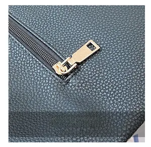 Detail shot of smooth golden metal zipper on high-quality black lychee grain leather bag