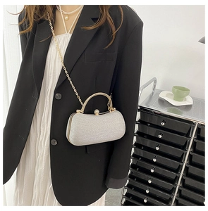 Silver glitter evening clutch featuring a gold round handle and rhinestone clasp detail