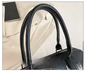 Dettaglio dei doppi manici in pelle e degli inserti argentati su una borsa nera chic