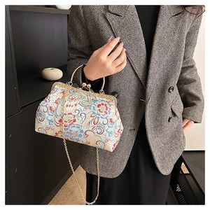 Detail of vintage floral embroidery on satin bag with golden metal frame clasp and chain