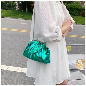 Gros plan d'un sac à main vert métallisé brillant avec chaîne argentée en extérieur