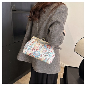 Detailed side view of an embroidered floral kiss-lock bag with a gold chain strap