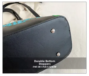 Dettaglio della borsa in pelle con ricami colorati e piedini protettivi in argento