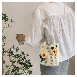 Detail of hand-crocheted bucket bag with 3D yellow flowers and white pearl strap