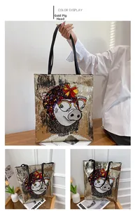 Detailed view of sequin tote bag with gold cartoon pig design and black leather handles