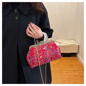 Close-up of red silk satin handbag with floral embroidery and golden metal frame
