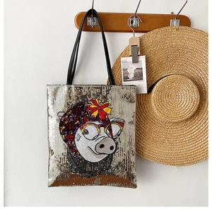 Detail of sequin tote bag with cartoon pig design on wooden hook in home setting