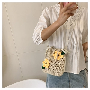 Detail of hand-knitted beige bucket bag with sunflower decor and pearl strap