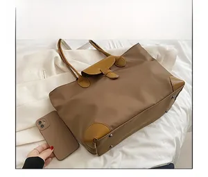 Size comparison between a brown oxford cloth tote bag and a smartphone on white fabric