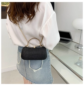 Detailed view of a black glitter evening bag with gold metal handle and chain strap