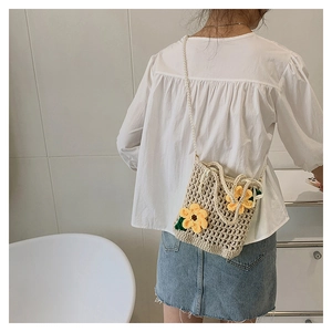 Detail of hand-woven beige bucket bag with yellow crochet flowers and pearl strap