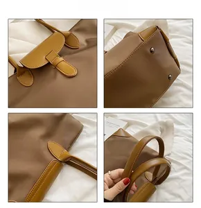 Close-up of brown nylon tote with leather flap, reinforced handle and metal bottom studs