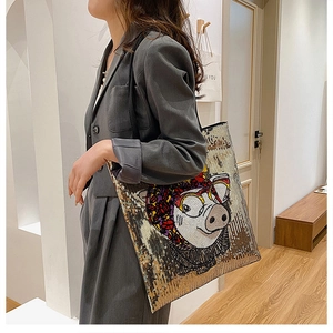 Detail of sequin tote bag with cartoon pig graphic and silver-gold shiny finish