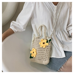 Detail of hand-knitted cream bucket bag with yellow sunflower and pearl strap