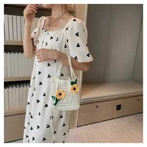 Detail of hand-woven bucket bag with yellow sunflower accents and pearl strap