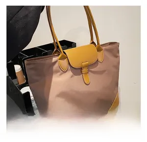 Detail showing high-capacity nylon tote bag with leather contrast stitching and buckle