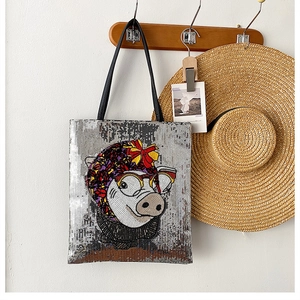 Detail of silver sequin tote bag with cartoon pig graphic on wooden coat rack