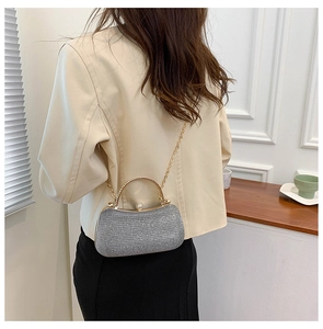 Detail of silver glitter evening bag featuring gold handle and chain strap on shoulder