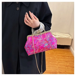 Detail of floral embroidery on magenta satin evening bag with vintage gold metal clasp