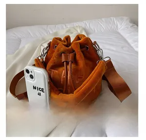 Orange velvet bucket bag with drawstring closure and size comparison to a phone