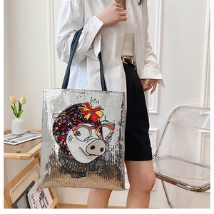 Detail of sequined tote bag featuring a cartoon pig design and long shoulder straps