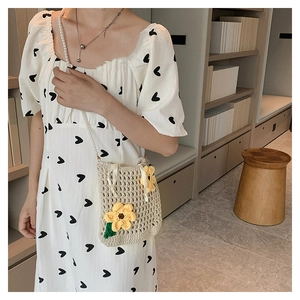 Detail of beige knitted bucket bag with yellow floral applique and pearl bead strap