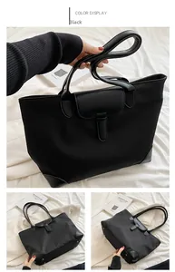 Detailed view of black nylon tote bag with leather straps and protective base studs