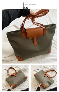 Detail of gray nylon tote bag featuring brown leather trim and metal corner rivets