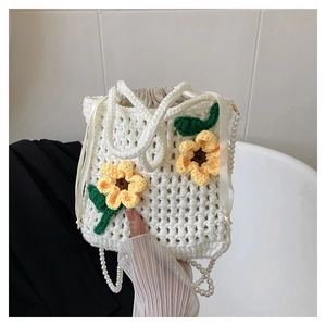 Detail of white crochet bucket bag with yellow sunflowers and pearl beaded shoulder strap
