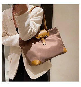 Detailed shot of a brown nylon tote bag with leather trim worn with a white blazer