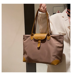 Detail of a large capacity brown nylon tote bag with high-quality leather handles and flap
