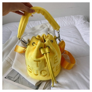 Detail of yellow plush bucket bag with THE BUCKET lettering and wide nylon strap