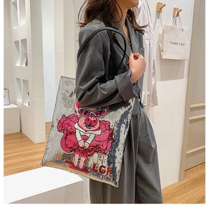 Detail of sequin tote bag featuring pink cartoon pig embroidery and leather handles