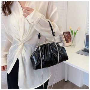 Détail de pochette plissée noire en cuir avec fermoir métallique argenté et chaîne